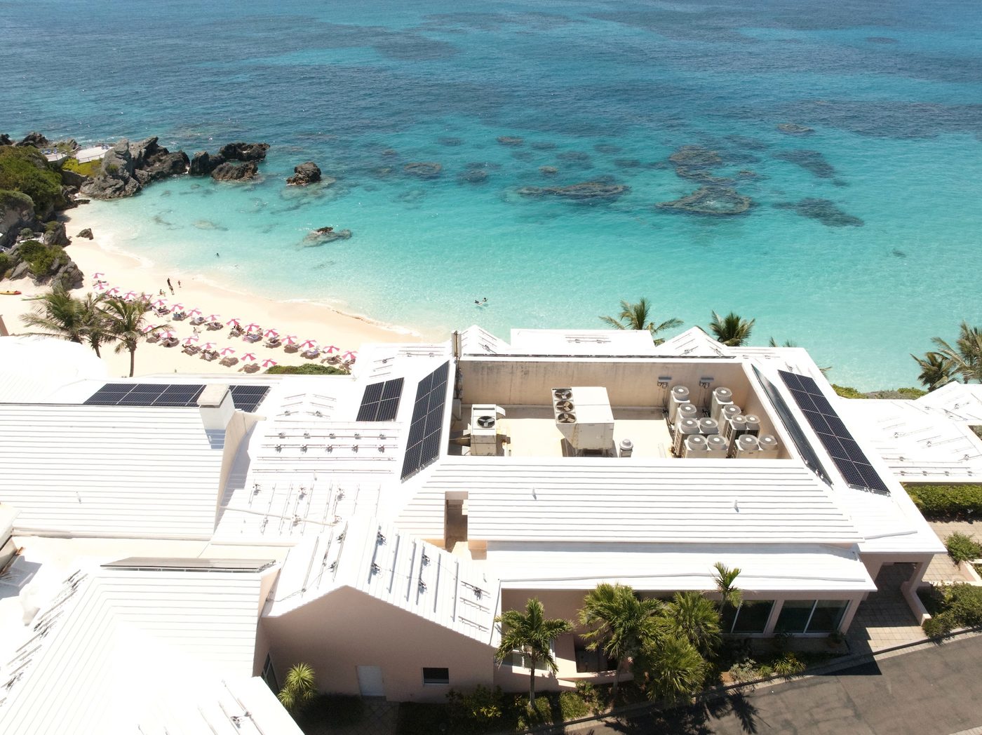 Coated commercial roof planes with solar arrays, beach beyond