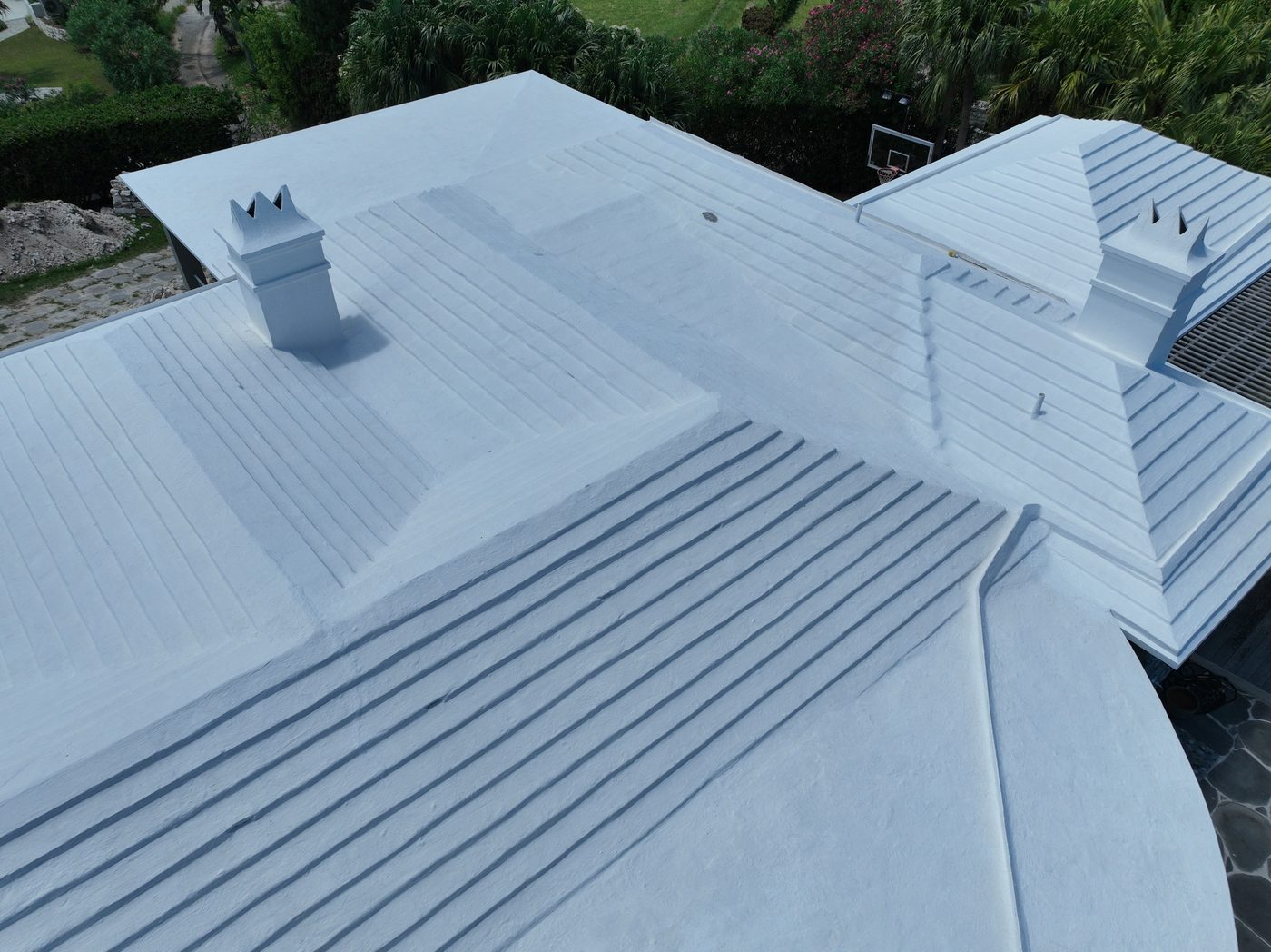 A restored white Bermuda roof on a house with a pool, harbour behind